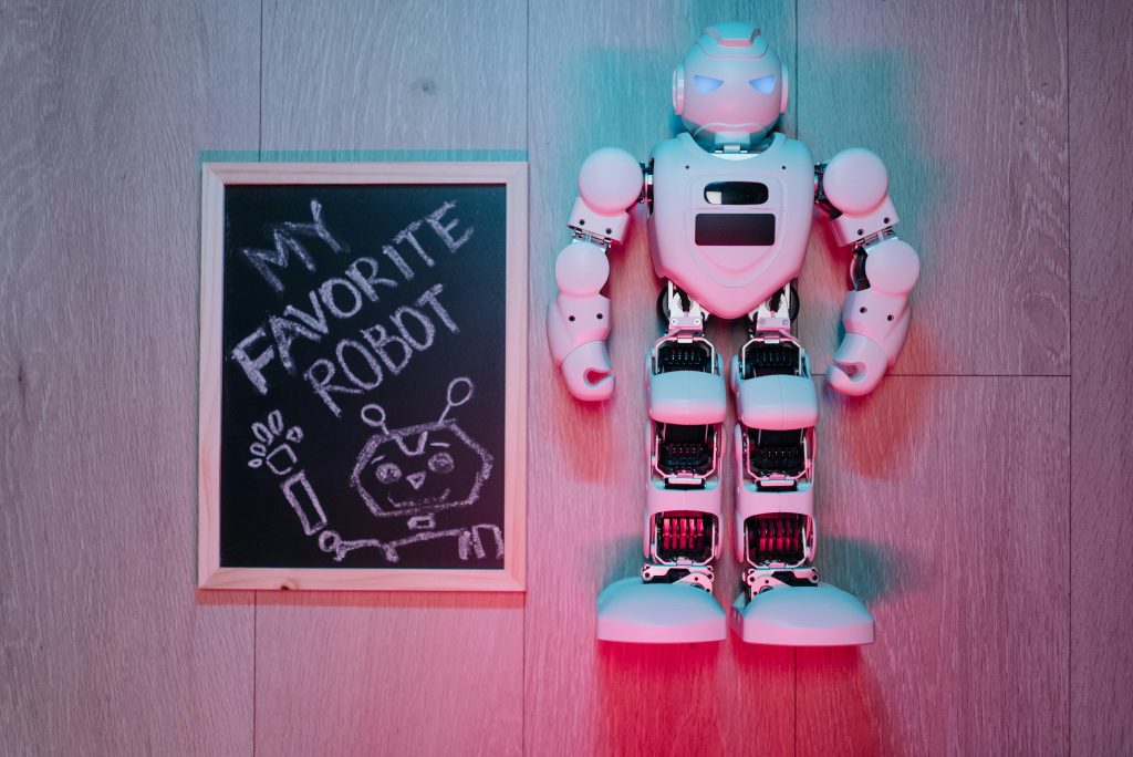Playful scene of a white robot toy and chalkboard drawing on wooden floor.